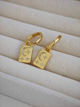 Goldene Ohrringe mit rechteckigen goldenen Platten als Anhänger, auf dem Anhänger sind Mond und Sterne abgebildet, Mond und Sterne haben Zirkonia Steine eingearbeitet